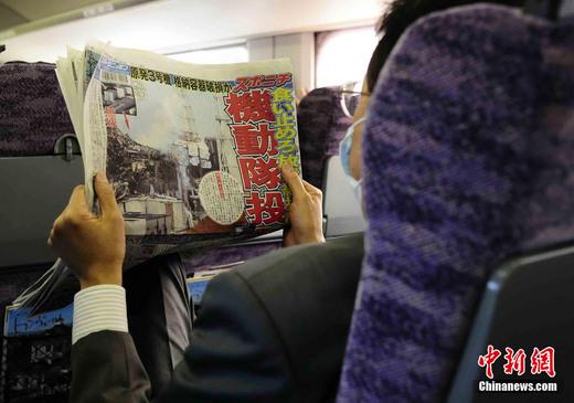 3月17日下午，在一列前往東京的新干線列車上，一名日本人在閱讀關于福島核電站三號機組最新狀況的報道。中新社發(fā) 侯宇 攝