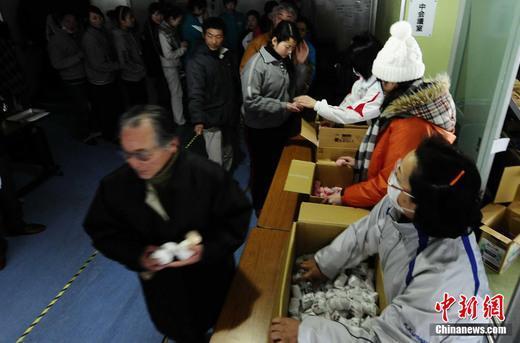 3月16日，在日本巖手縣大船渡地區(qū)公民會館避難的民眾排隊領取食物。中新社發(fā) 侯宇 攝
