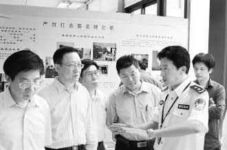 圖為公安部經(jīng)偵局副局長高峰(右)向公安部特邀監(jiān)督員們介紹“亮劍”行動展覽情況。 