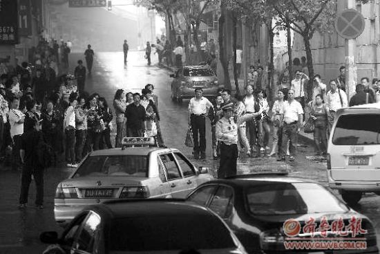  8日，在青島15中考點(diǎn)外，家長排起人墻堵路，交警只能指揮途經(jīng)車輛繞行。 本報記者 楊寧 張曉鵬 攝