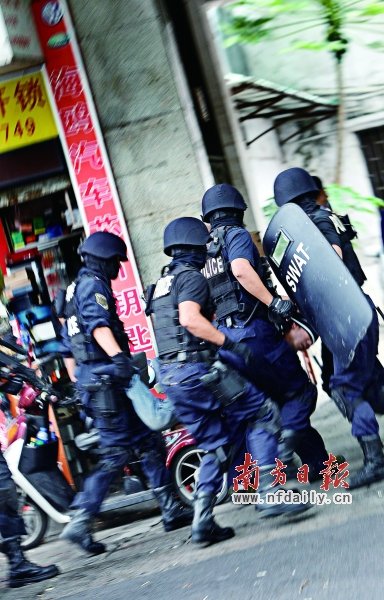 特警將嫌疑人（紅圈內(nèi)）押上警車。