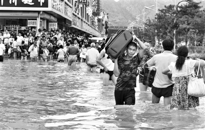 昨日，一名消防戰(zhàn)士在秦皇島市山海關(guān)火車站站前廣場涉水幫助旅客運送行李。 新華社發(fā)