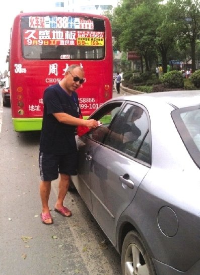 8月17日，邵陽(yáng)市西湖路與寶慶路交接處，穿拖鞋戴墨鏡的市容監(jiān)督員在對(duì)占?jí)喊唏R線停放的車(chē)輛罰款。圖/記者龍?jiān)? hspace=