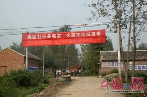 死者的家屬在村口迎接前來(lái)吊唁的親友，紅色的橫幅看上去更具諷刺意味。