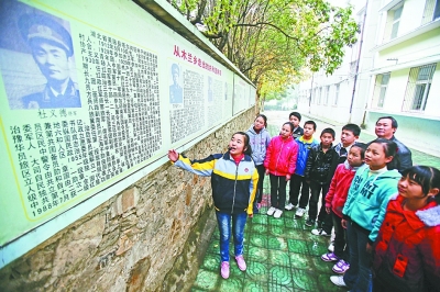 上圖：學(xué)校文化墻前，小講解員講述開(kāi)國(guó)將軍杜義德的故事。記者何曉剛 攝
