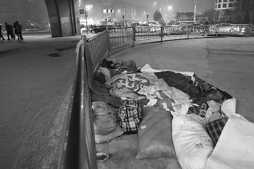 農(nóng)民工露宿地的不遠處，夜幕下車來車往