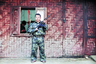 老三手持自己在前線用的半自動(dòng)步槍站在居住的小屋外。