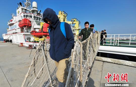 圖為24名“驢友”的“導游”被邊防的工作人員帶下船接受調(diào)查。 駱云飛 攝