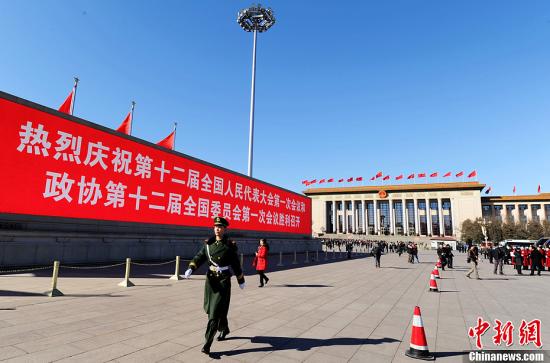 3月4日，北京晴空萬里，武警從北京天安門廣場(chǎng)大型顯示屏前走過。3月5日上午，十二屆全國(guó)人大一次會(huì)議將隆重開幕。中新社發(fā) 劉忠俊 攝