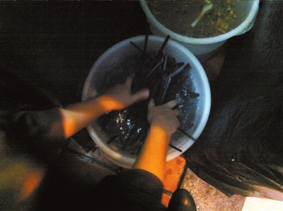 筷子泡過(guò)后用水簡(jiǎn)單沖過(guò)便被再次使用，旁邊是盛放垃圾的桶。