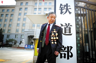 3月14日，鐵道部大門口，一位胸前掛著多枚勛章的鐵道部老職工與鐵道部牌子合影。 新京報(bào)記者 侯少卿 攝