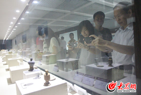 采訪團(tuán)的記者們拍攝隨元代古沉船共同挖掘出土的文物，他們對(duì)這些文物很感興趣。