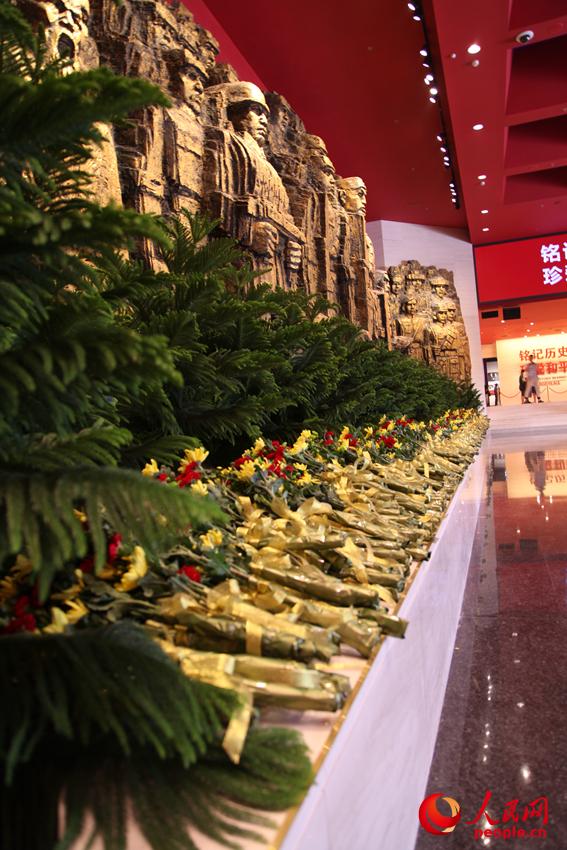 紀(jì)念館門廳的《銅墻鐵壁》雕塑墻，和人們獻(xiàn)上的花。邱越攝